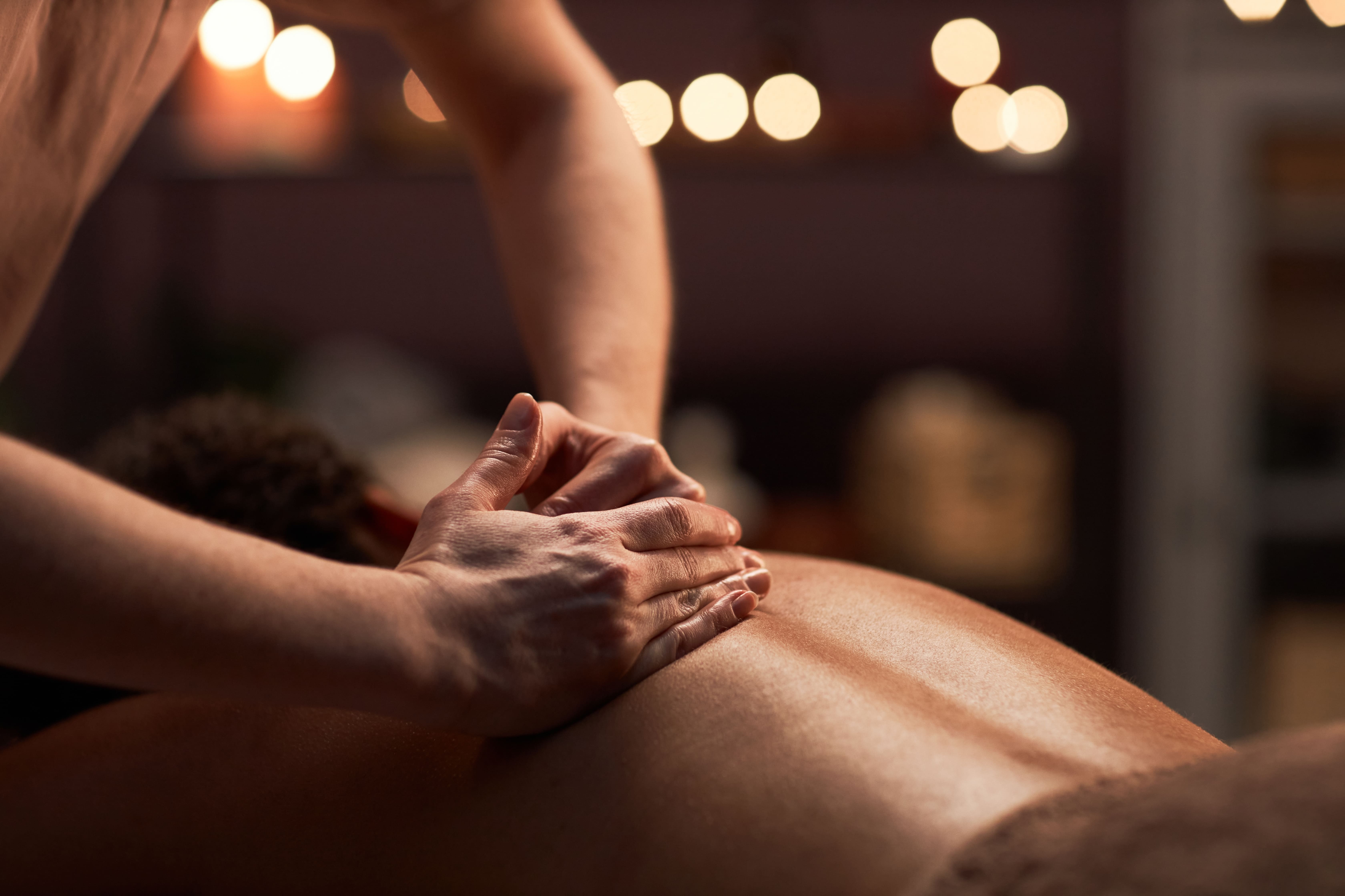 Therapeutic back massage being given in a warmly lit studio